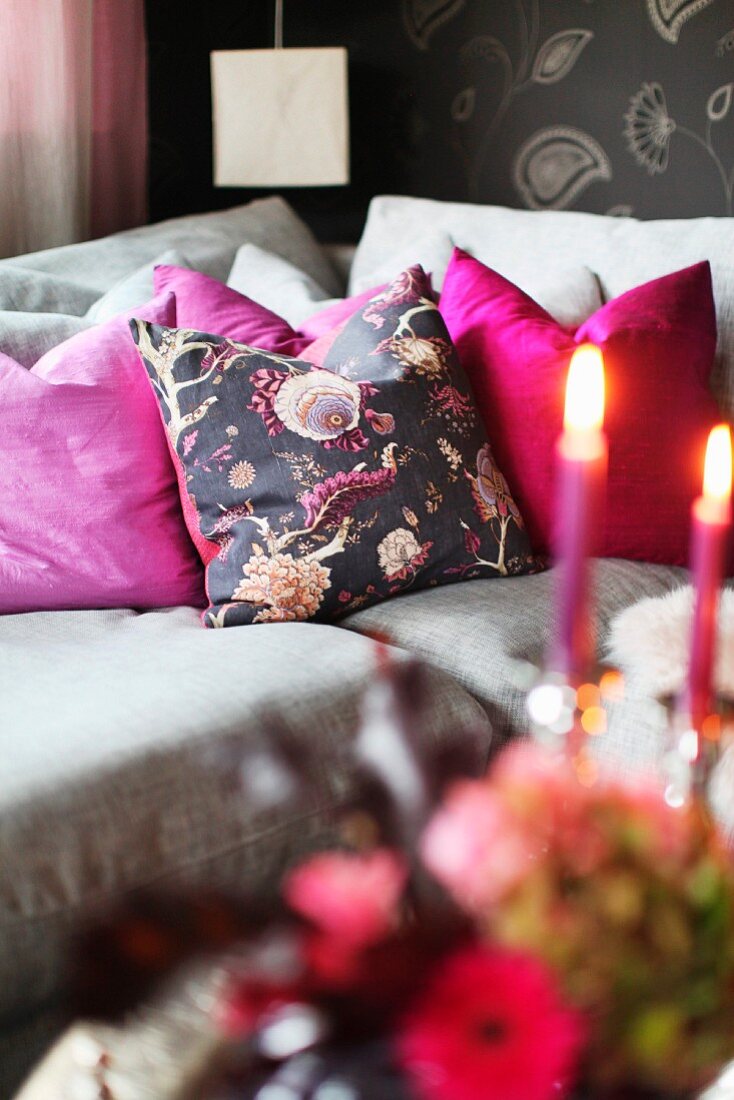 Grey sofa with pink scatter cushions and romantic lit candles in foreground