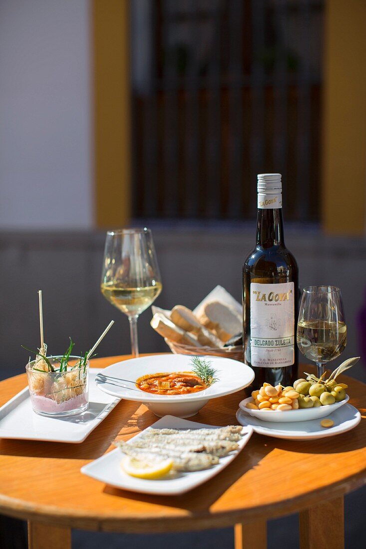 Fried fish, bean soup, olives and wine on a table in a restaurant