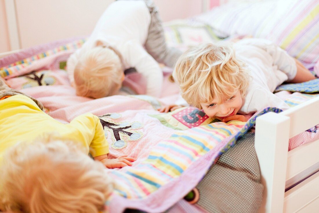 Three young brothers crawling face down on bed