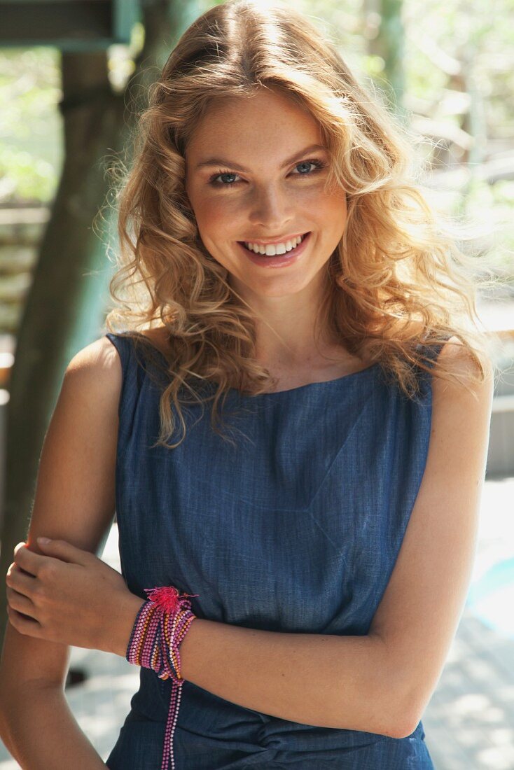 A young blonde woman outside wearing a blue summer dress