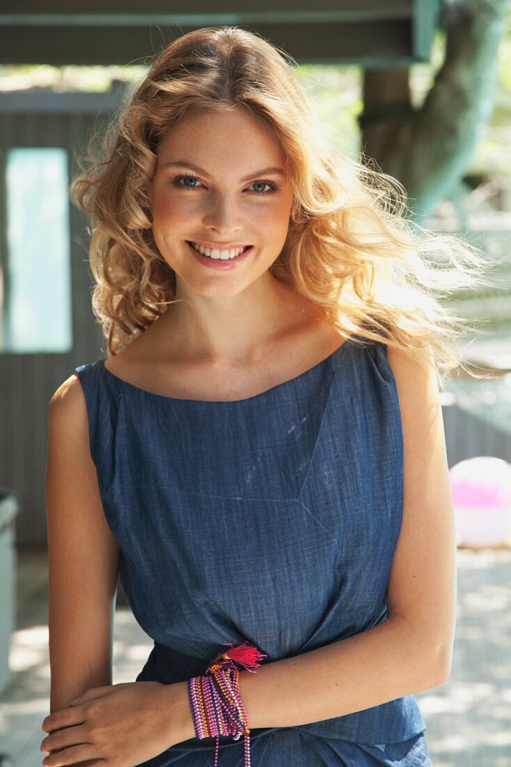 A young blonde woman outside wearing a blue summer dress