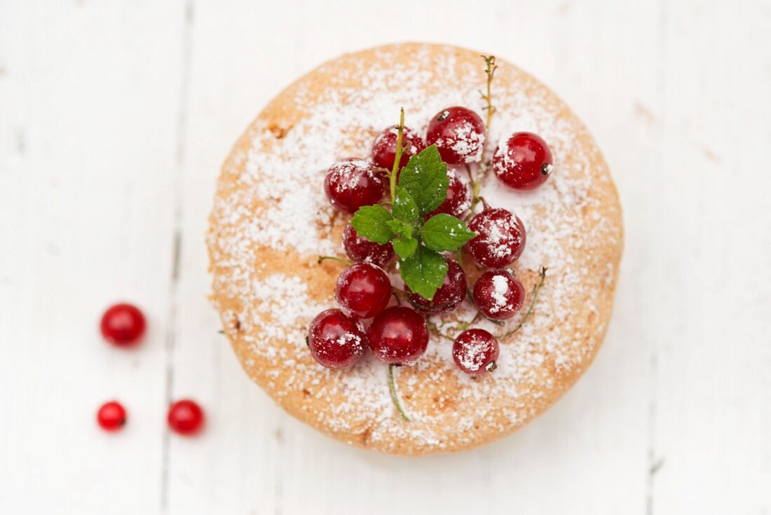 A mini cake with redcurrants and icing sugar