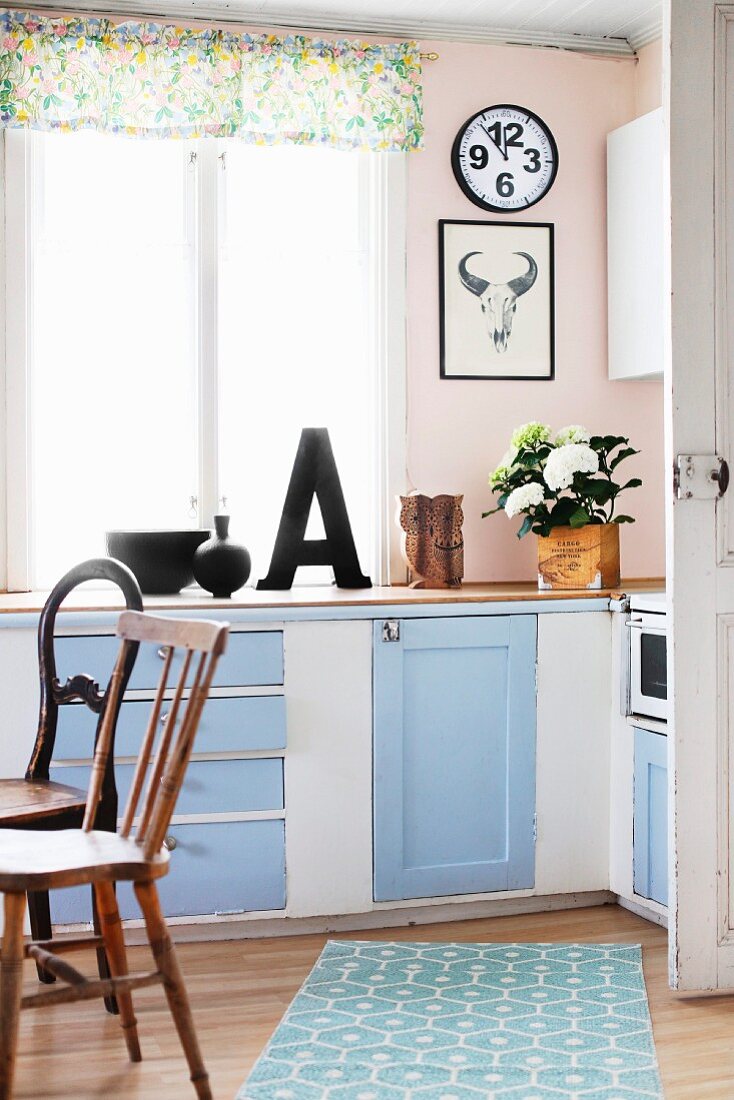 Nostalgische einfache Landhausküche in hellblau und weiß mit verschiedenen naturbelassenen Holzstühlen