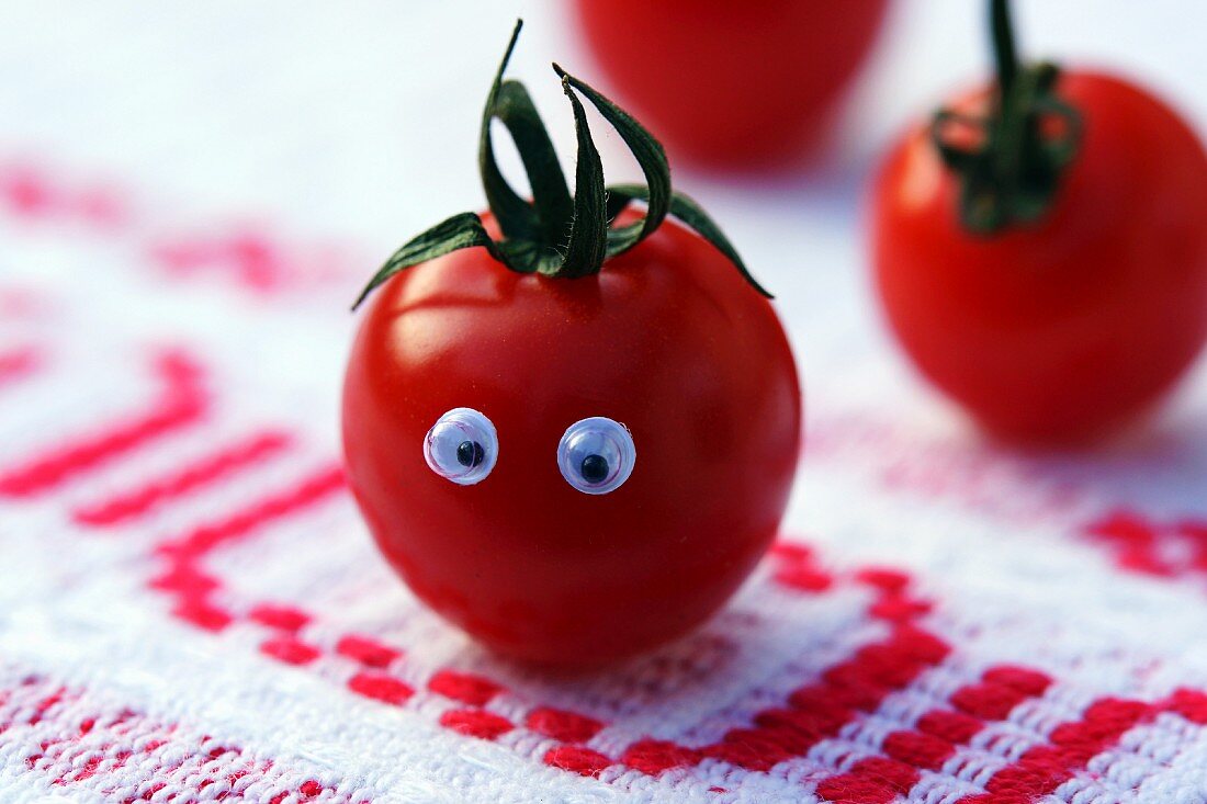 Tomate mit Gesicht auf rustikalem Tischtuch