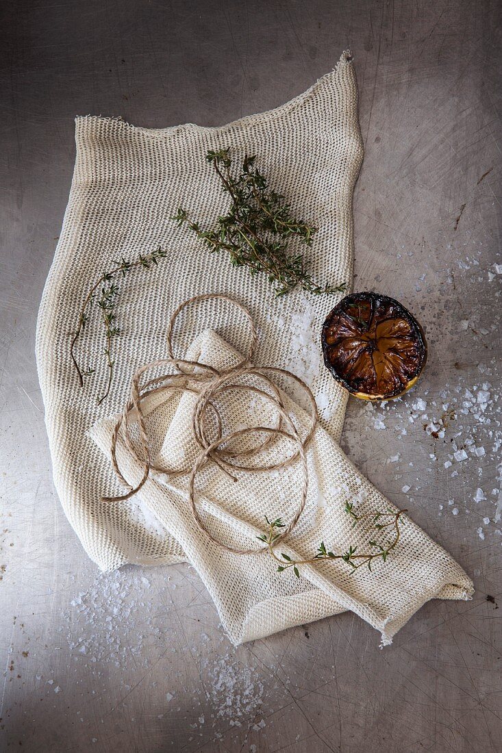 Kitchen twine, thyme and half a lemon on a cloth