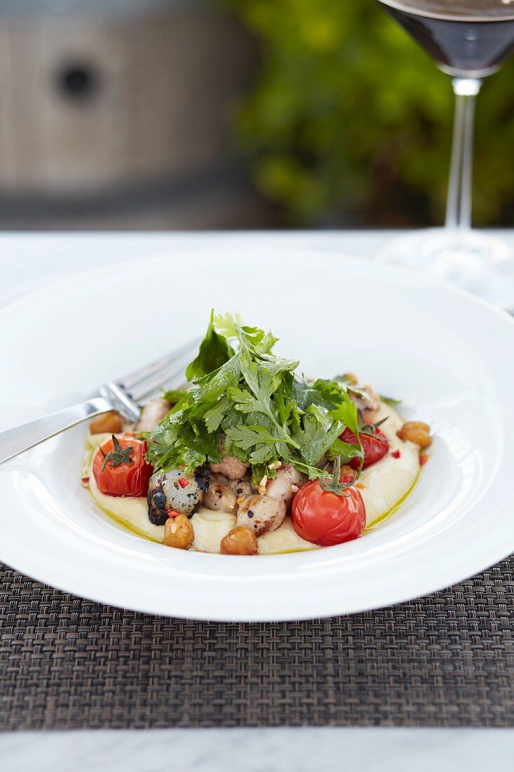 Kalbsbries, gebratene Tomaten und Petersilie auf Hummus