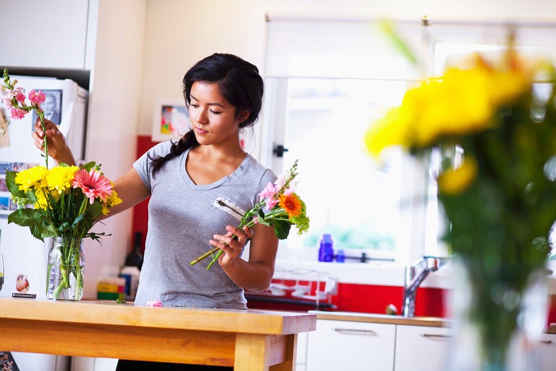 Junge Frau arrangiert Blumen in der Küche