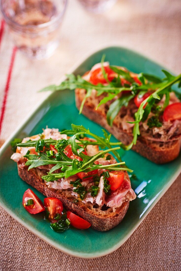 Slices of bread topped with spread, tomatoes and rocket