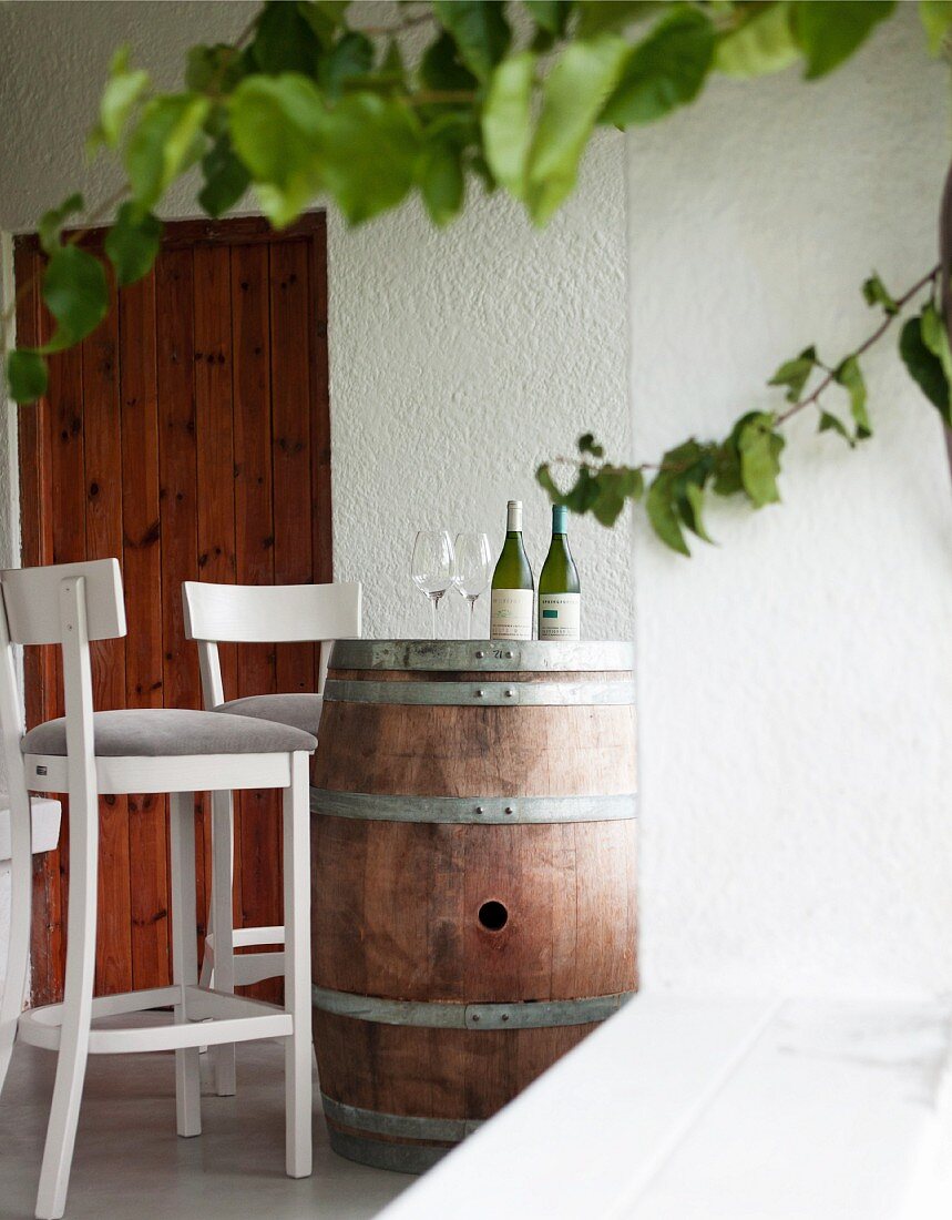 Weissweinflaschen und -gläser auf Fass im Weinverkostungsraum