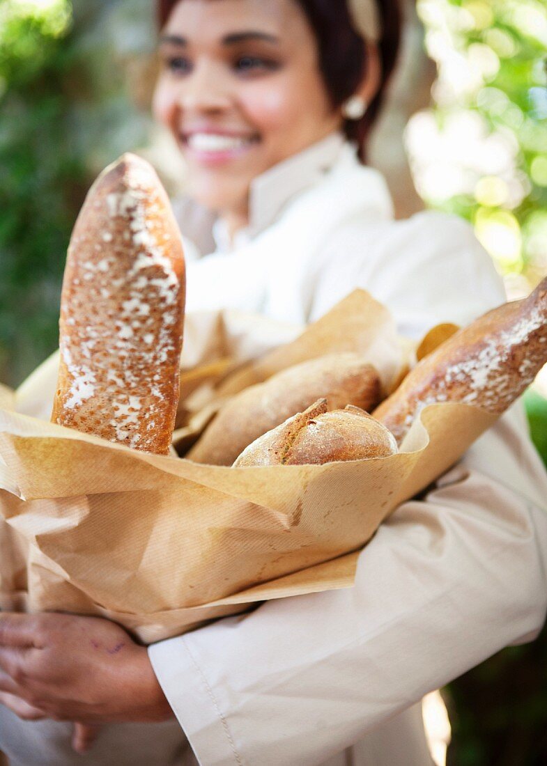 A woman holding a bag of baguettes