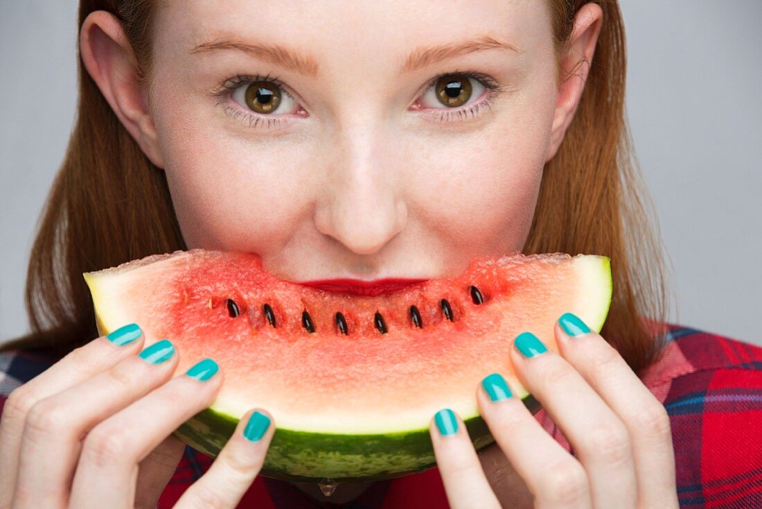A young woman biting into a slice of watermelon