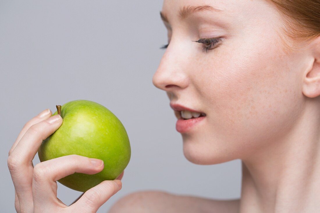 Porträt einer jungen Frau mit grünem Apfel