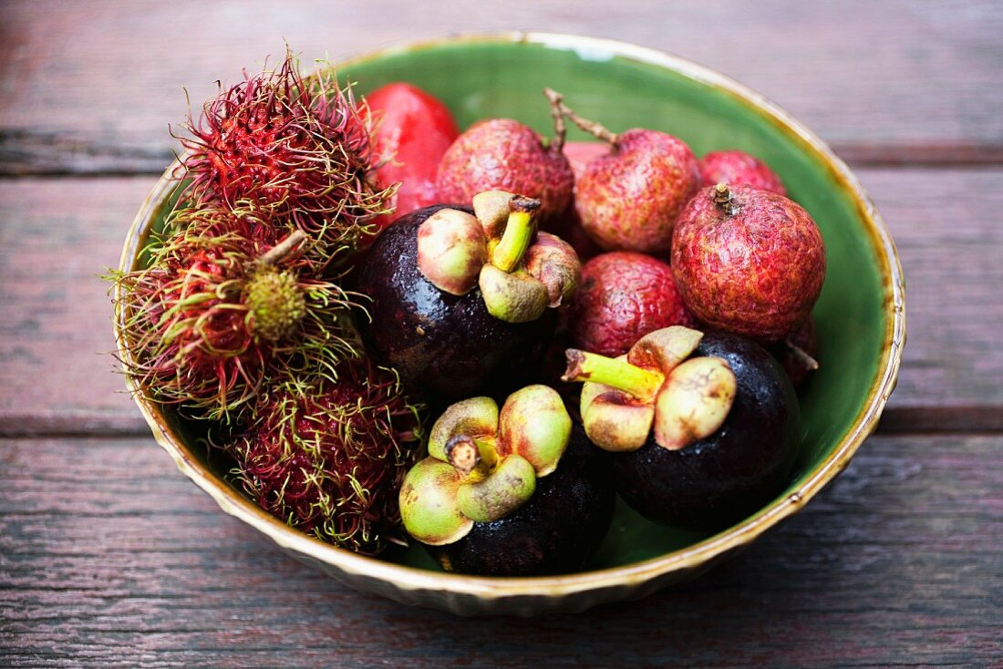 Exotic fruits in a green ceramic bowl