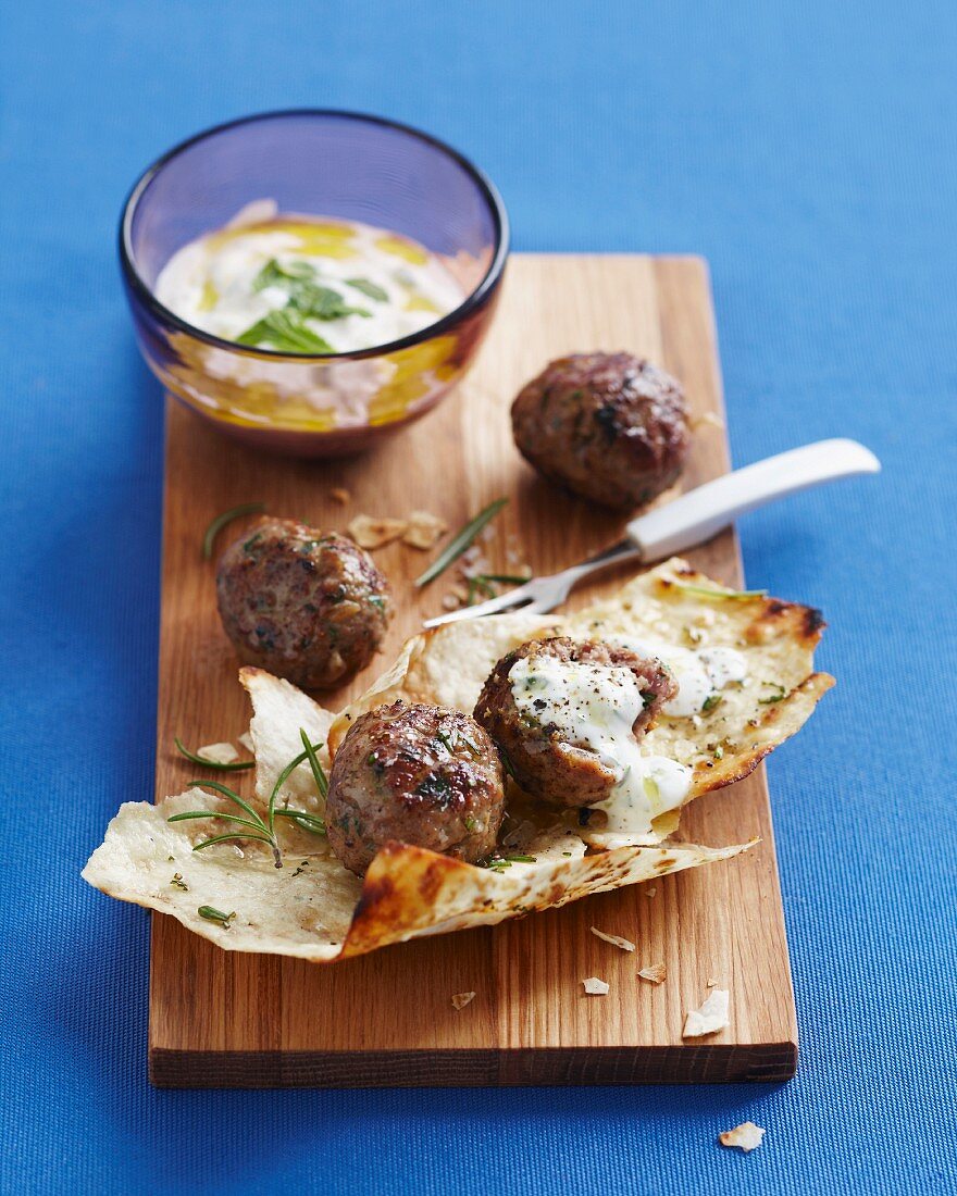 Lebanese meatballs on a chopping board with a dip