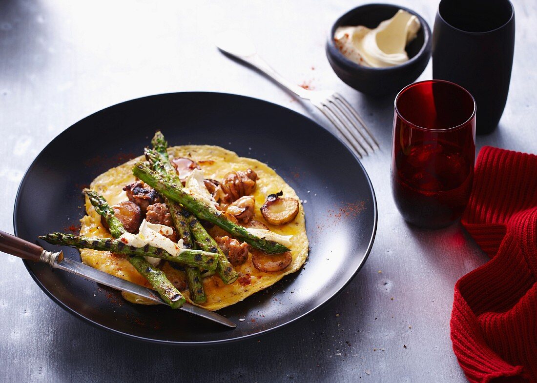 Omelette mit grünem Spargel serviert auf einem schwarzen Teller