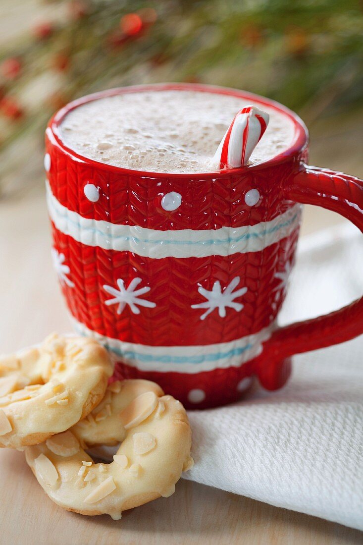 Hot chocolate in a red and white cup served with white chocolate biscuits