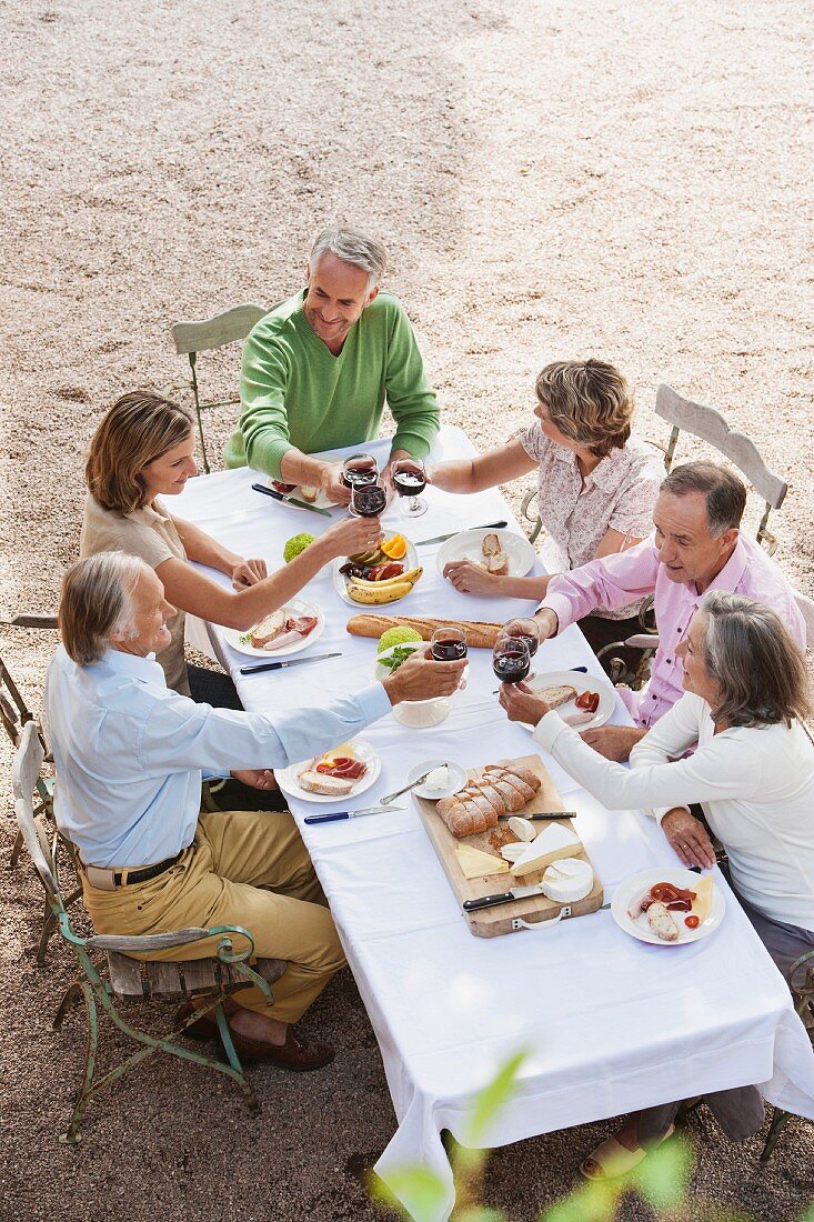 Blick auf drei Paare mittleren Alters im Freien bei Essen und Rotwein