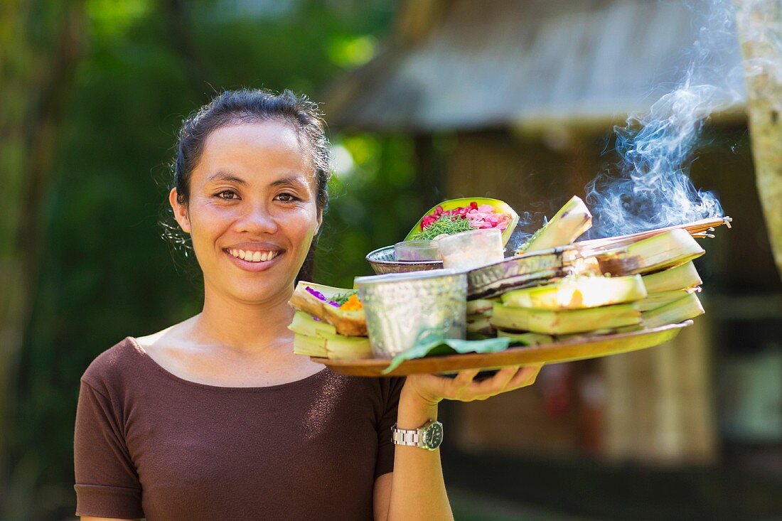 Balinesische Frau hält Tablett voller Essen