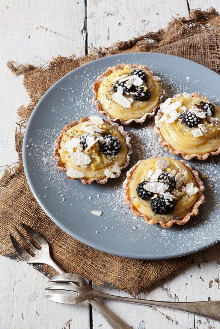 Blackberry tartlets with lemon cream, flaked almonds and icing sugar
