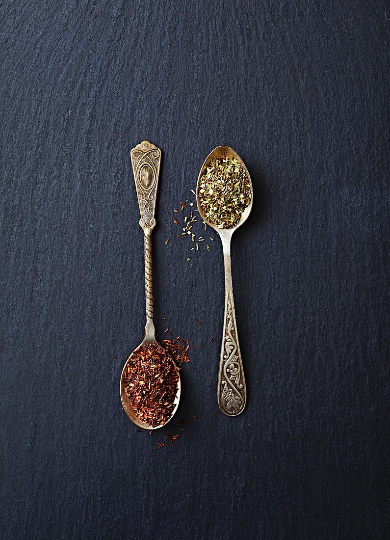 Dried green and red rooibos tea on spoons