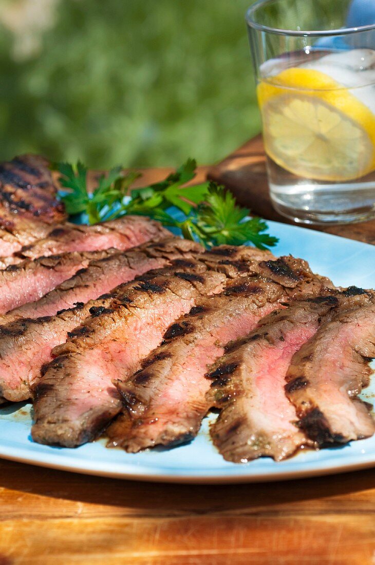 Sliced Grilled Flank Steak on a Blue Platter
