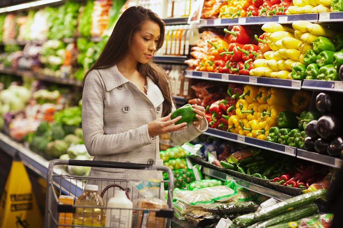 Junge Frau in der Gemüseabteilung eines Supermarktes