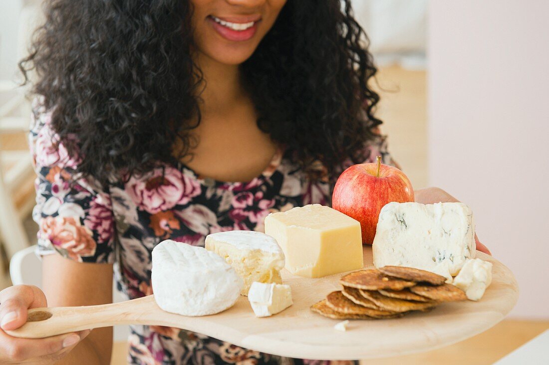 A young woman carrying a cheese board