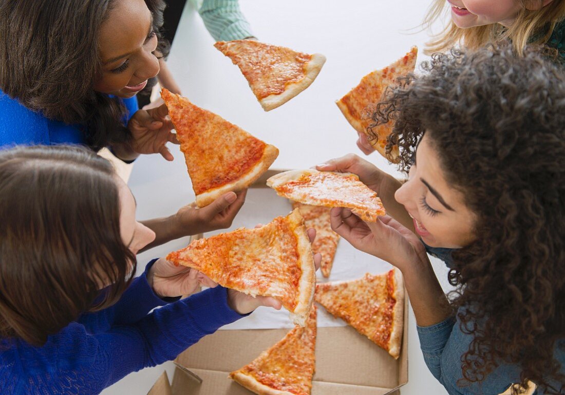 Women eating pizza together with their hands