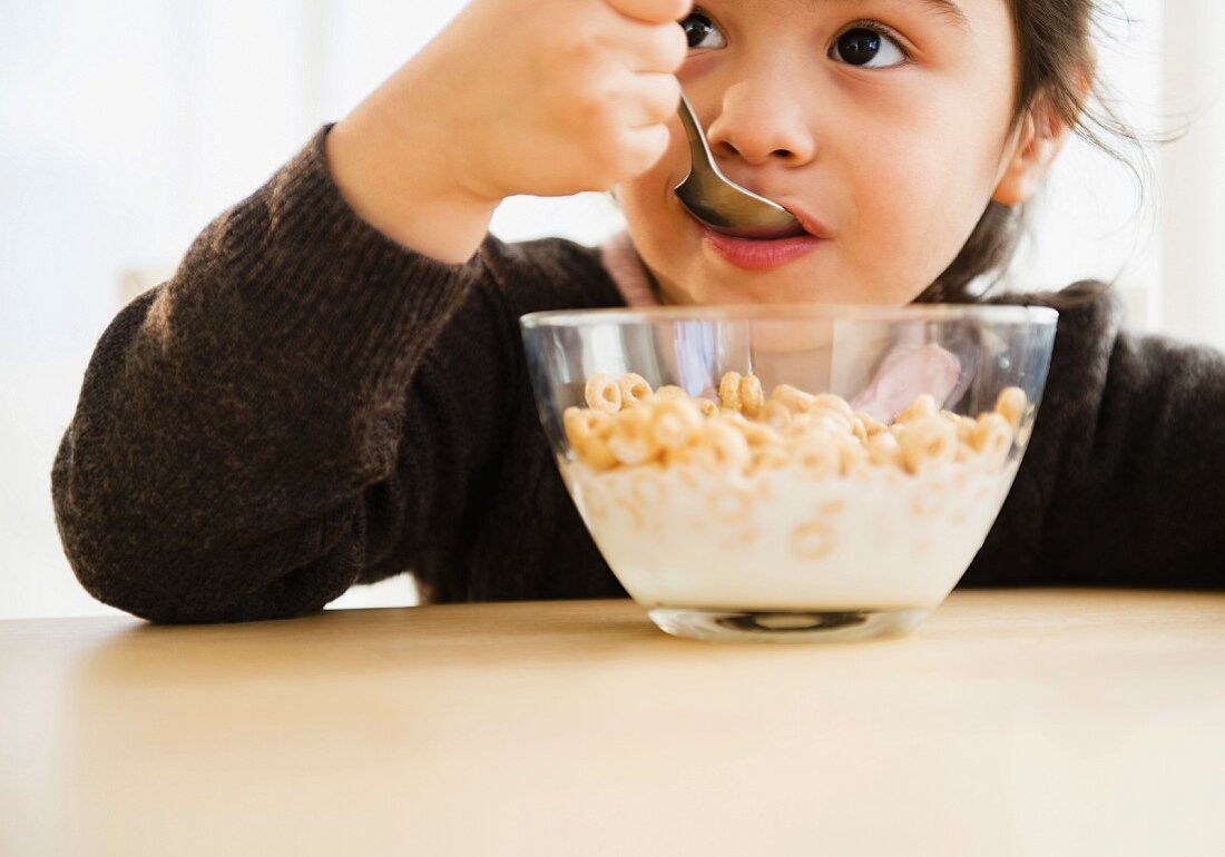 Kleines Mädchen isst aus Schale mit Cerealien
