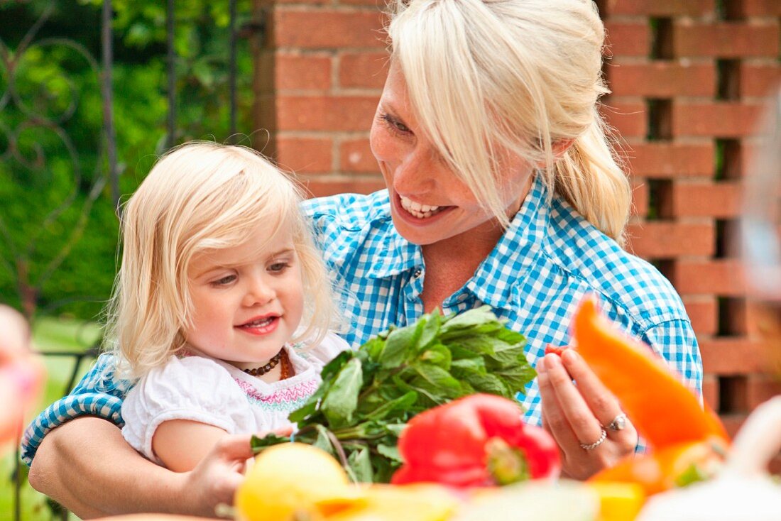 Mutter und Kleinkind am Gartentisch mit Gemüse