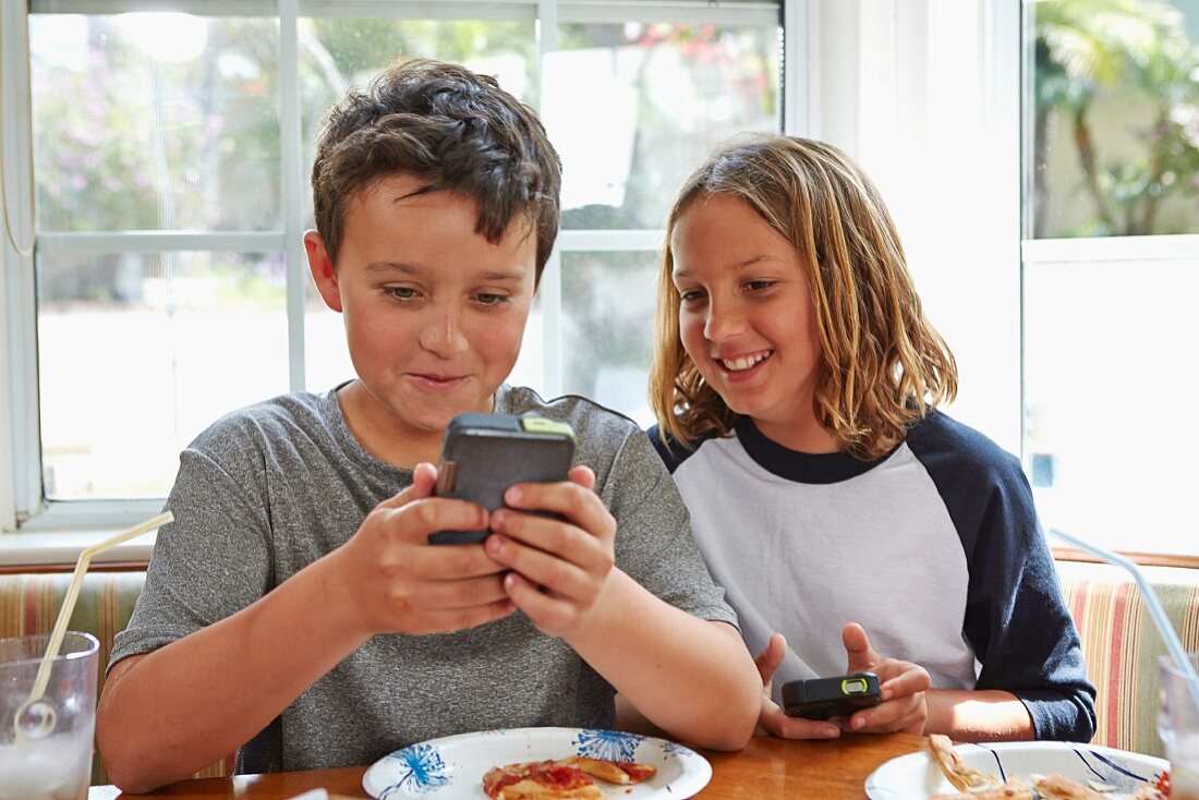 Two boys at the dining table playing video games