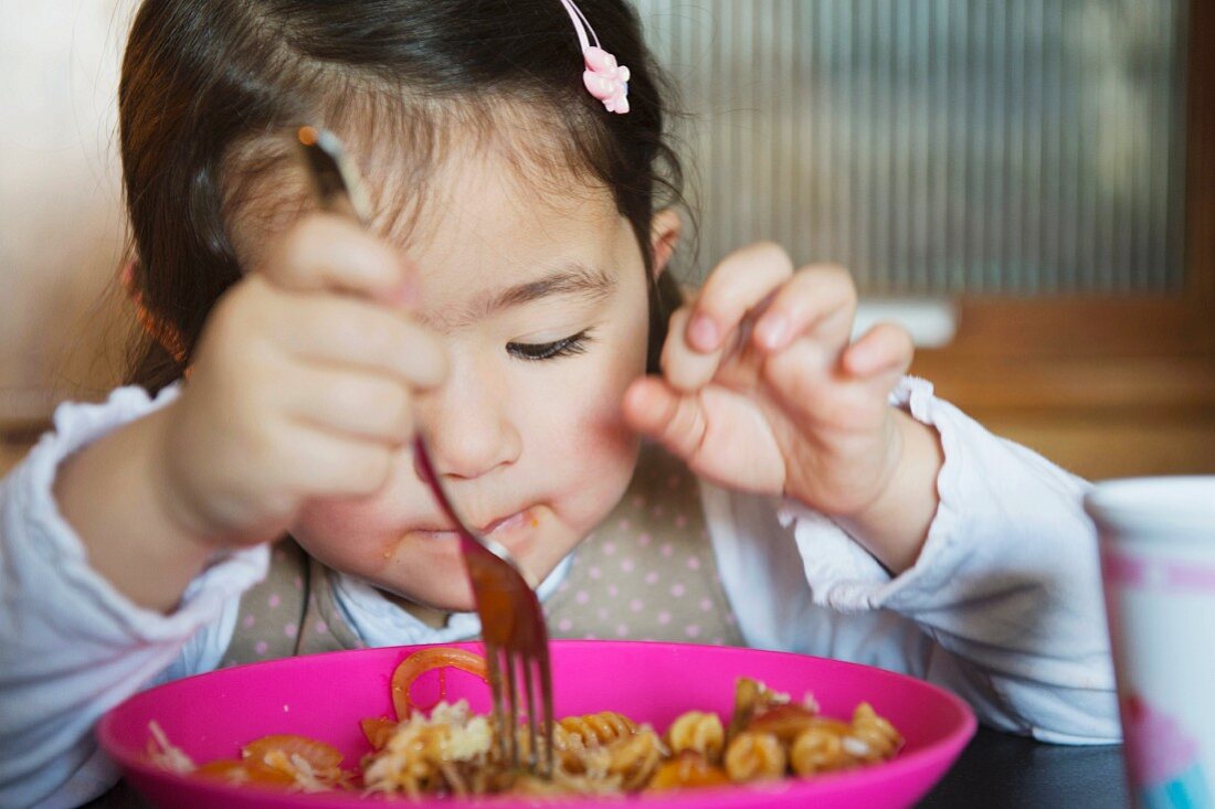 Kleines Mädchen isst Pasta mit Gabel
