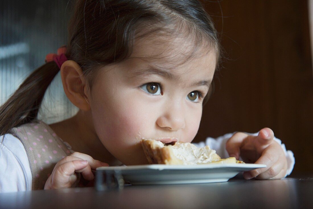 A little girl eating cake directly off the plate