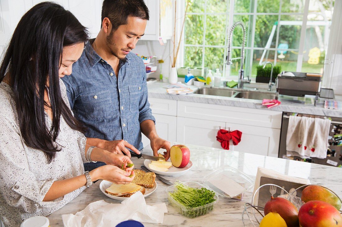 Junges asiatisches Paar bereitet Sandwich in der Küche