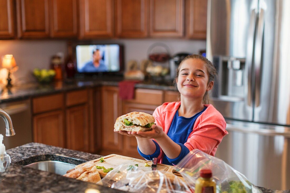 A little girl in a kitchen making a sandwich