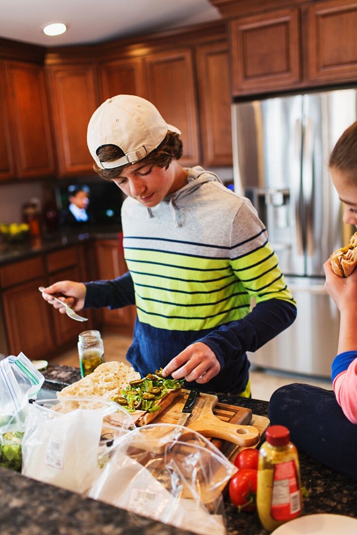 A brother and a sister in a kitchen making sandwiches