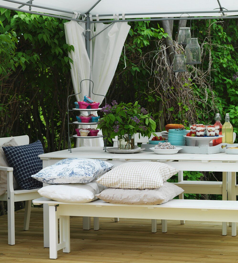 Nachspeisenbuffet auf weißem Tisch unter zeltartigem Pavillon auf der Terrasse