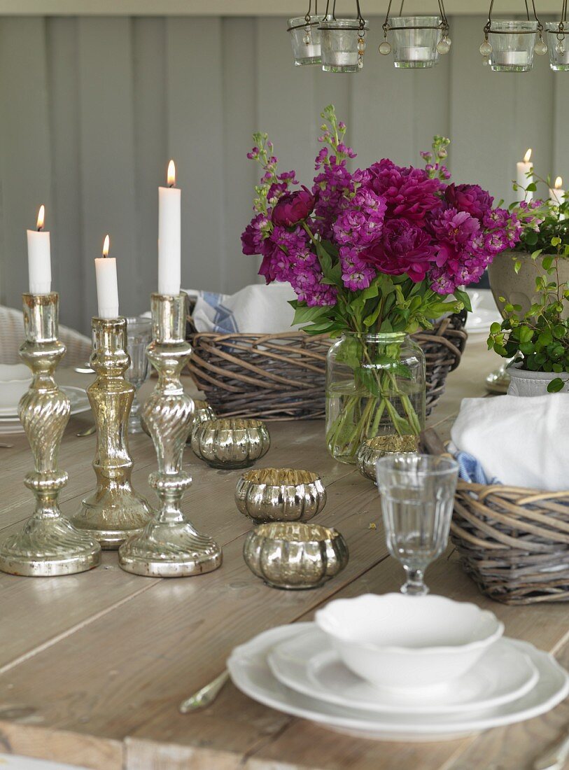 Silber Kerzenhalter mit brennenden Kerzen auf gedecktem Tisch in ländlichem Ambiente