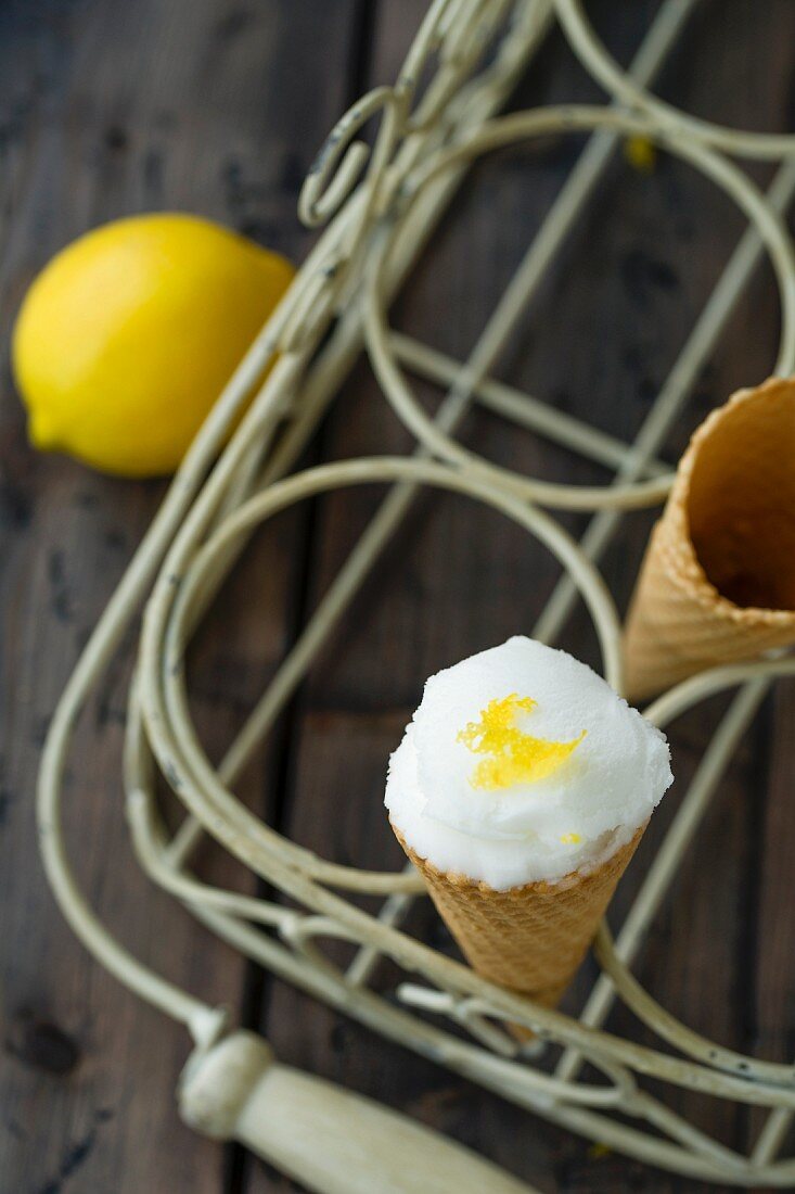 A scoop of lemon sorbet in an ice cream cone in a cone holder