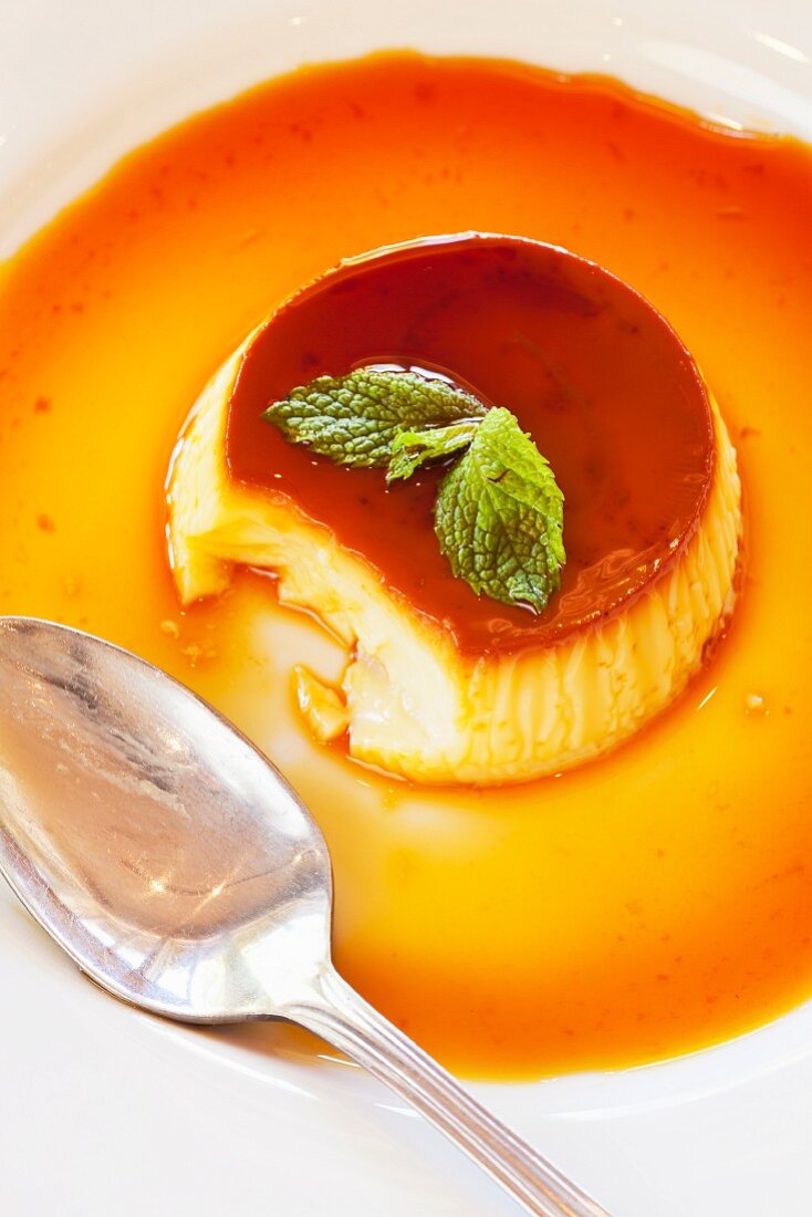Creme caramel garnished with mint leaves with a bite taken out