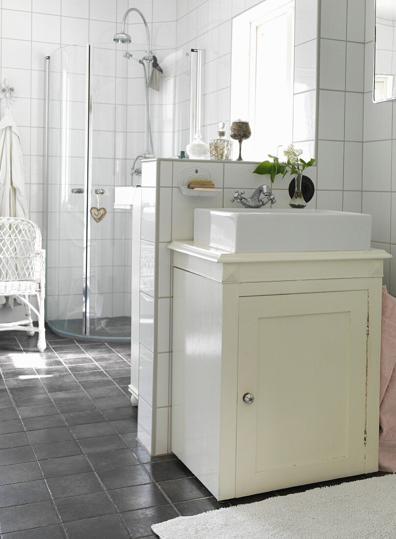 Rustic washstand against half-height wall in white-tiled bathroom