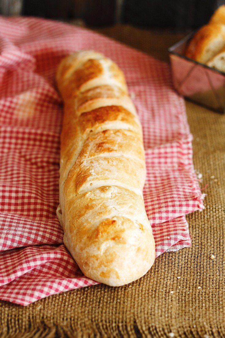 A loaf of French bread on red-and-white checked cloth
