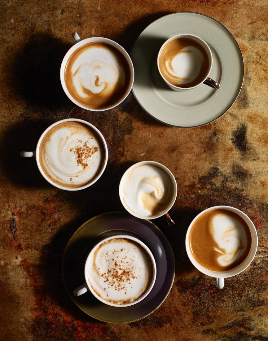 Cups of coffee with milk foam and cinnamon