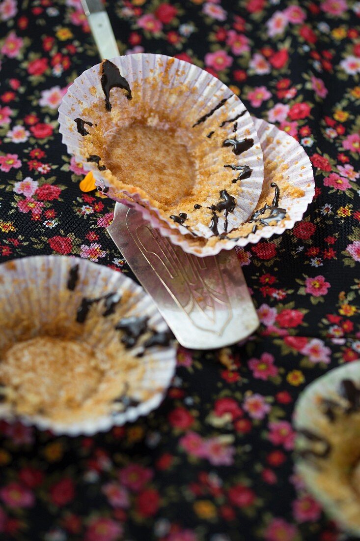 Leere Cupcakehüllen mit Krümeln und Schokolade