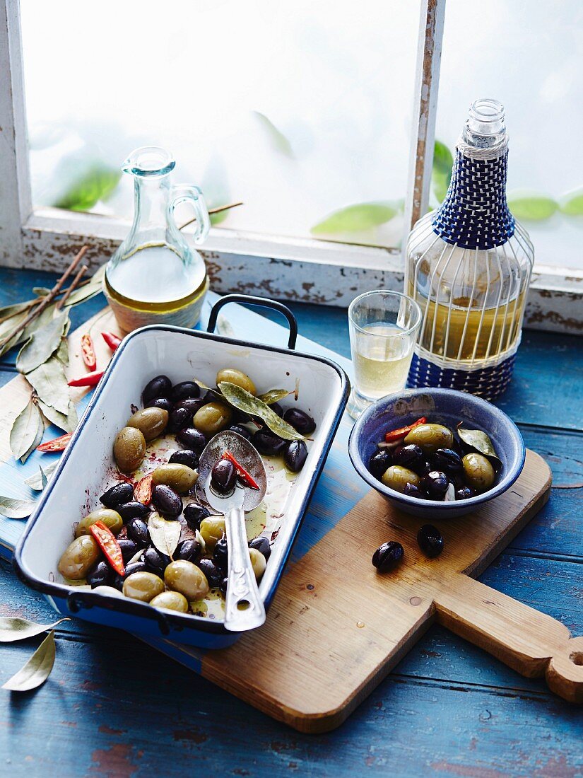 Marinated green and black olives in a roasting tin and in a bowl
