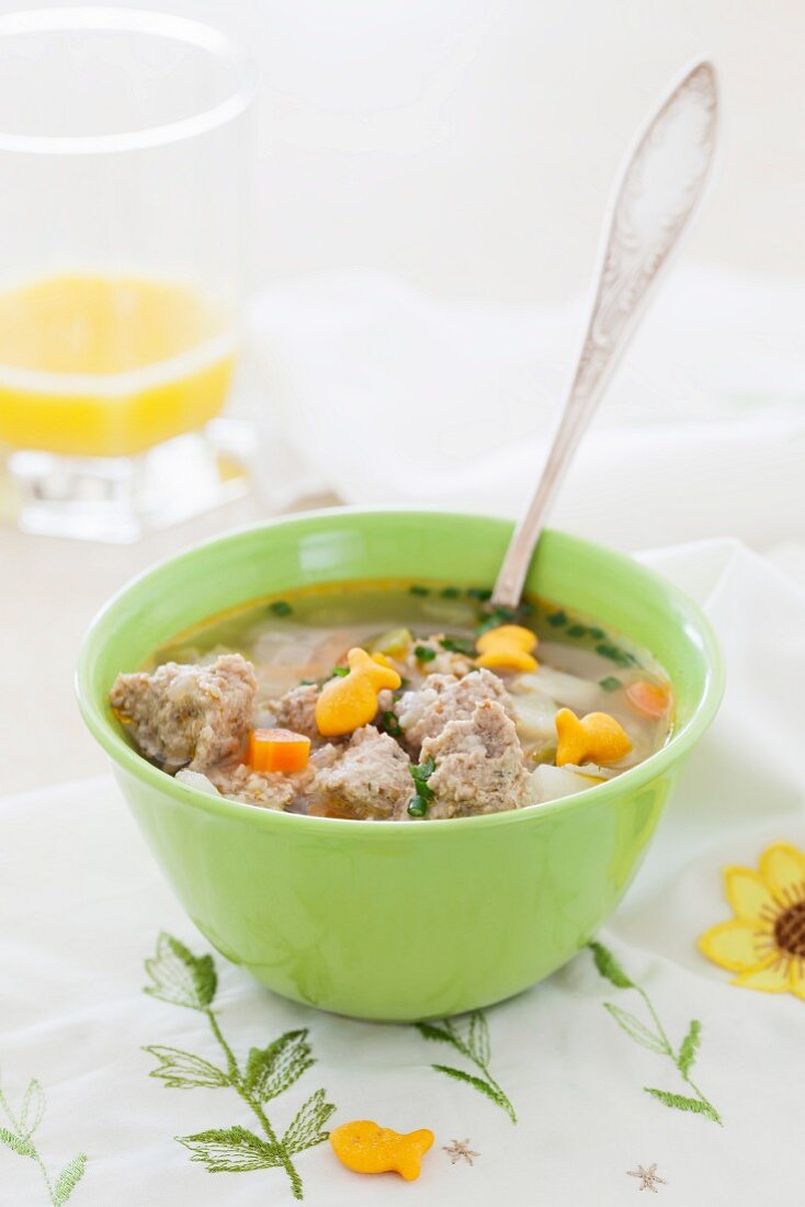 Chicken meatball soup with vegetables and fish-shaped crackers