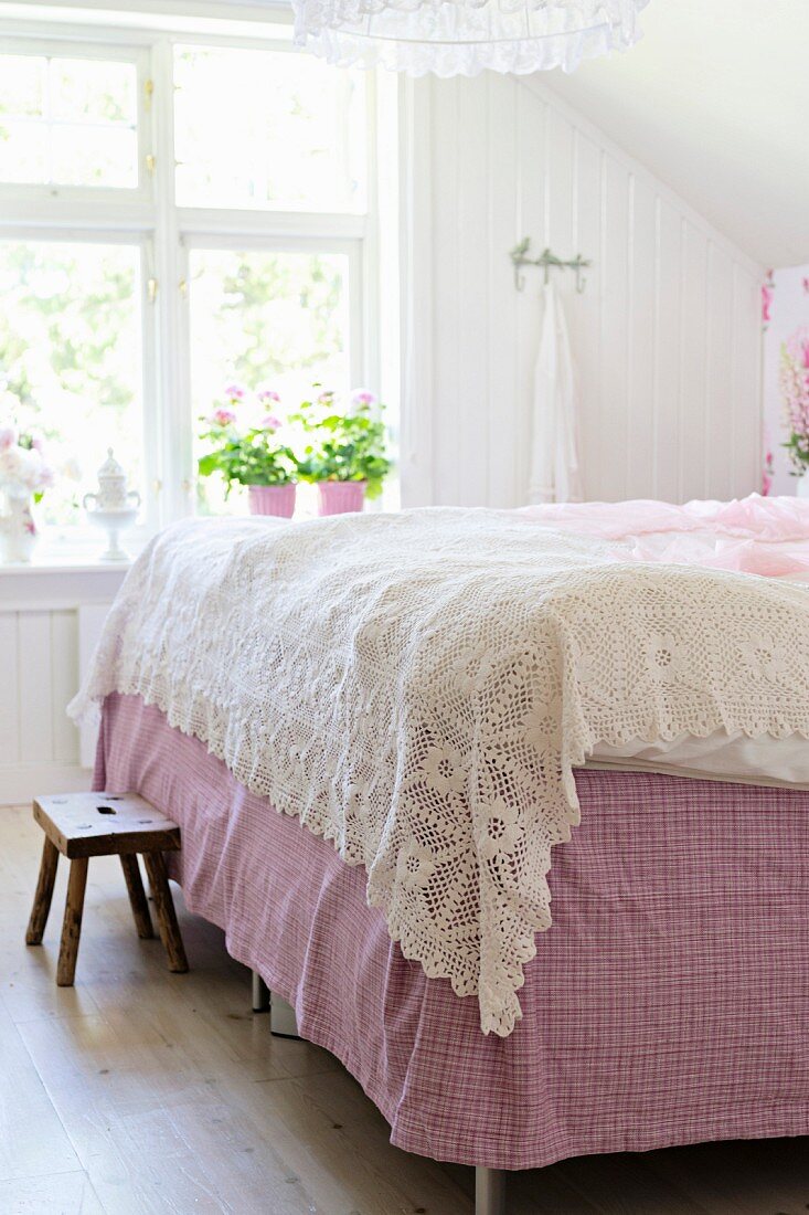 Gehäkelte, weiße Tagesdecke auf Doppelbett in ländlichem Schlafzimmer
