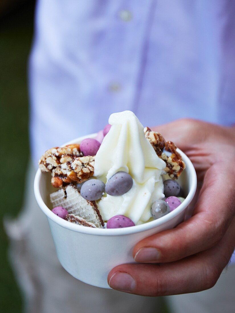 A hand holding a cup of frozen yogurt