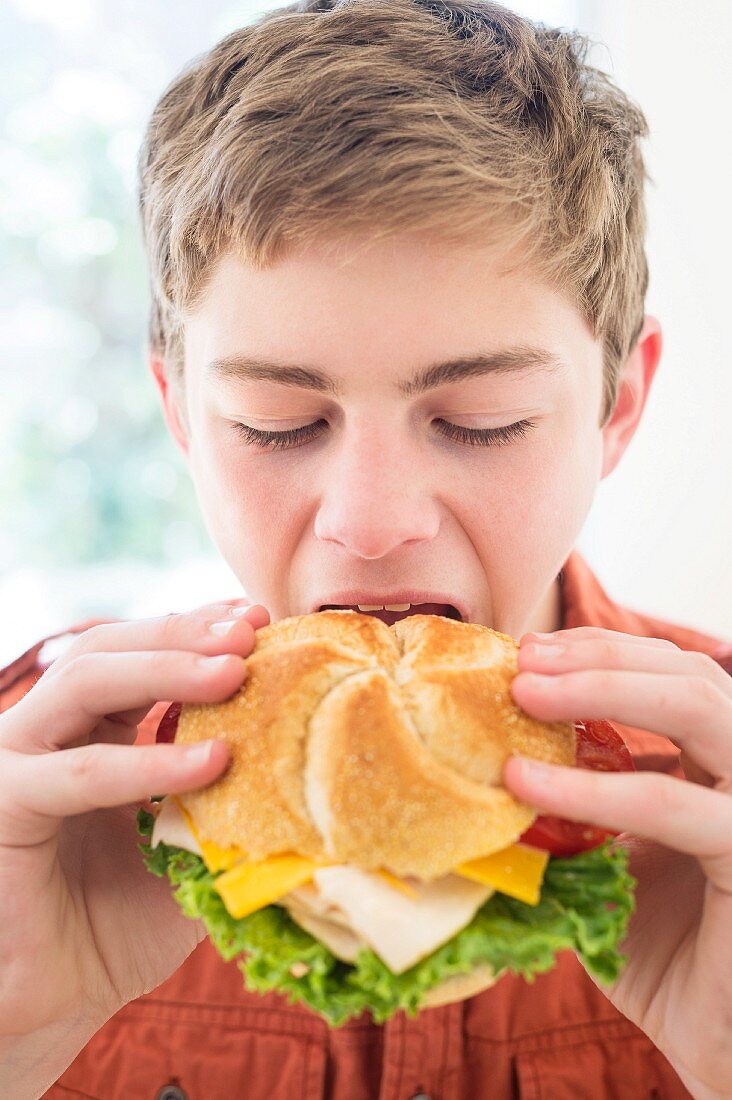 A teenager biting into a cheeseburger