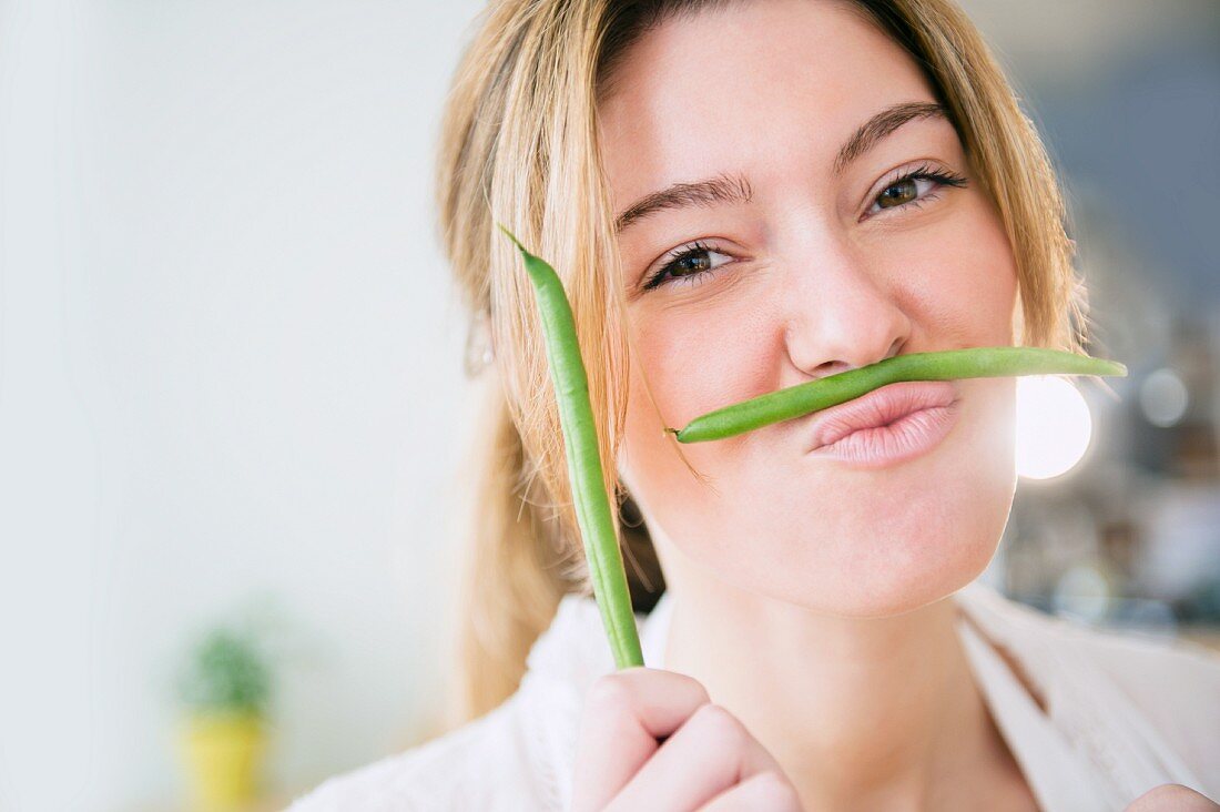 A young woman holding a green bean